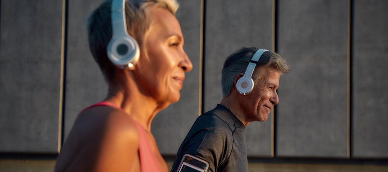 Pareja madura corriendo con auriculares mientras escucha podcasts sobre longevidad
